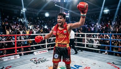 Indian boxer celebrating victory in professional ring with dramatic stadium lights
