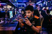 Young Indian gamer playing mobile game on smartphone in competitive setting