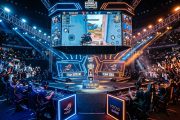 High-energy esports tournament arena with massive screens showing mobile game gameplay