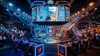 High-energy esports tournament arena with massive screens showing mobile game gameplay