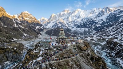 Himalayan temple shrine among snow-capped mountains with pilgrims on mountain path