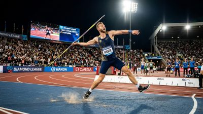 Javelin thrower in mid-throw at a professional Diamond League athletics stadium