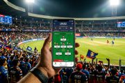 Smartphone showing fantasy cricket app with player stats against packed cricket stadium