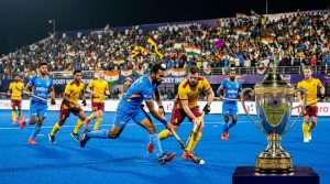 Intense field hockey match in packed Indian stadium with championship trophy
