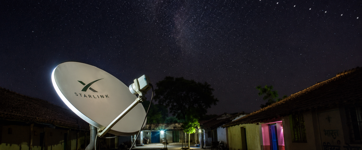 Satellite dish in rural India receiving internet signal from Starlink constellation in night sky