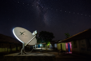 Satellite dish in rural India receiving internet signal from Starlink constellation in night sky