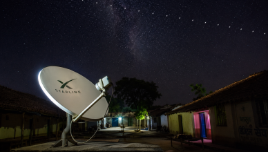 Satellite dish in rural India receiving internet signal from Starlink constellation in night sky
