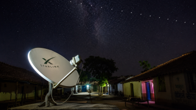Satellite dish in rural India receiving internet signal from Starlink constellation in night sky